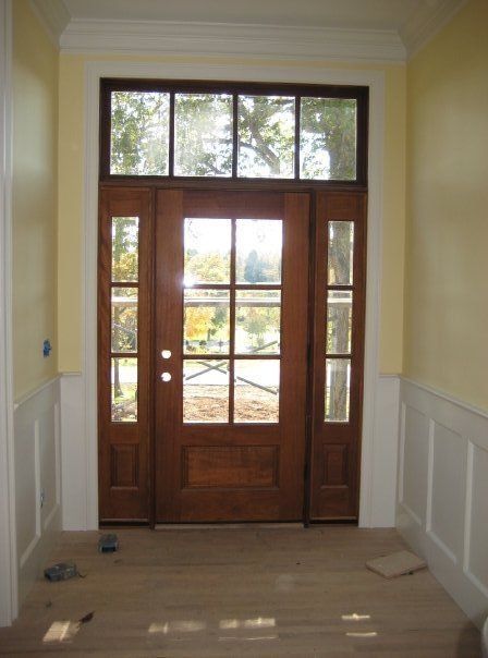Wooden front door with glass panes and sidelights in a bright hallway