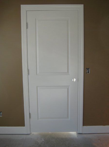 White paneled door on a brown wall in an empty room
