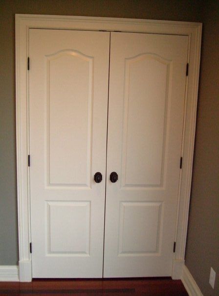 White double closet doors with black knobs in a beige room