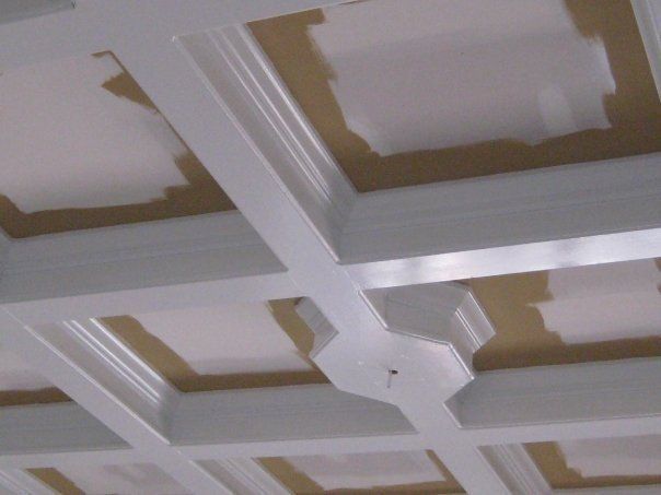 White coffered ceiling with geometric beams and tan recessed panels under construction