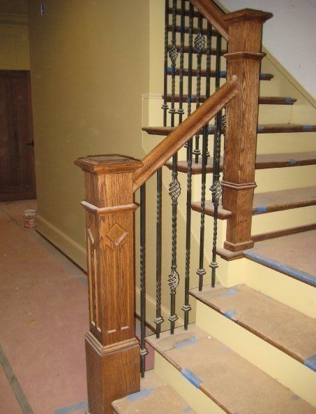 Wooden staircase with decorative metal balusters and carpeted steps in an indoor home hallway