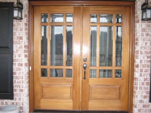 Wooden double front doors with glass panels set in a brick exterior wall
