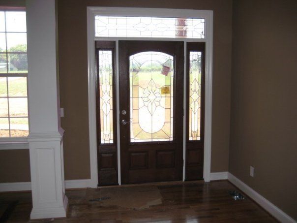 Front entry with wooden door, frosted glass panels, and side windows in a bright hallway