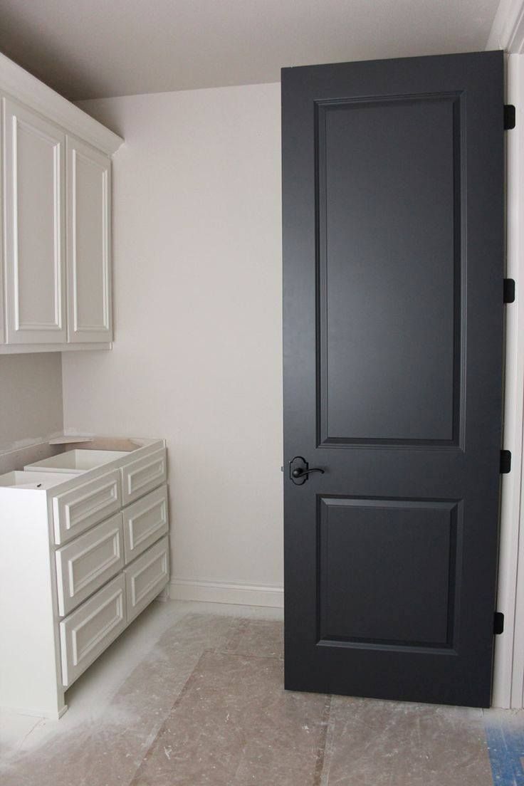 Small white bathroom with dark gray door, white cabinets, and light carpeted floor.