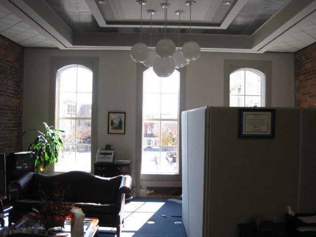 Sunny office lobby with leather sofas, potted plant, and large arched windows.