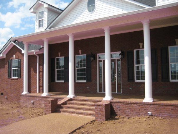 Brick house front porch with white columns, steps, and a ramp entrance