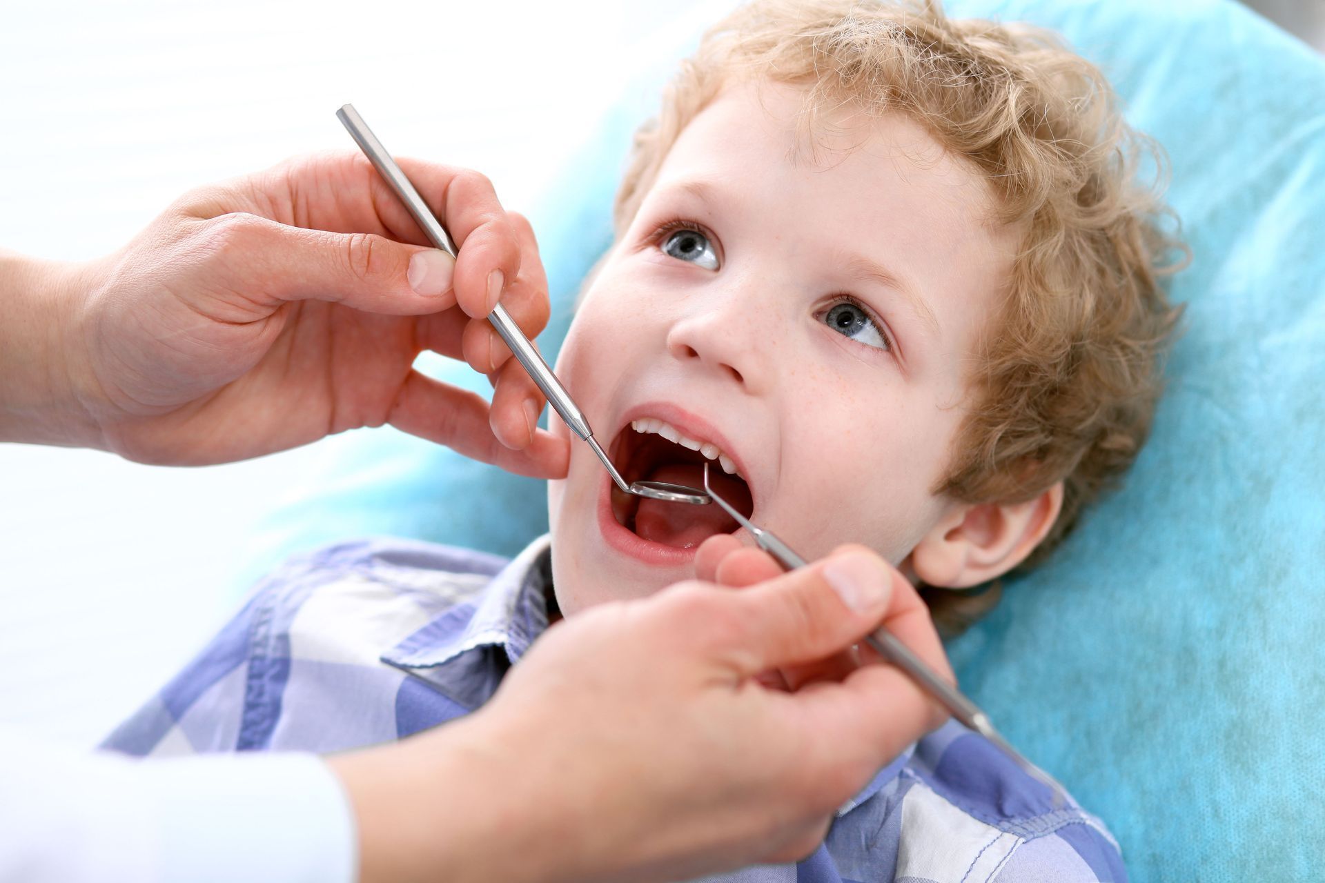 A young boy is getting his teeth examined by a dentist.