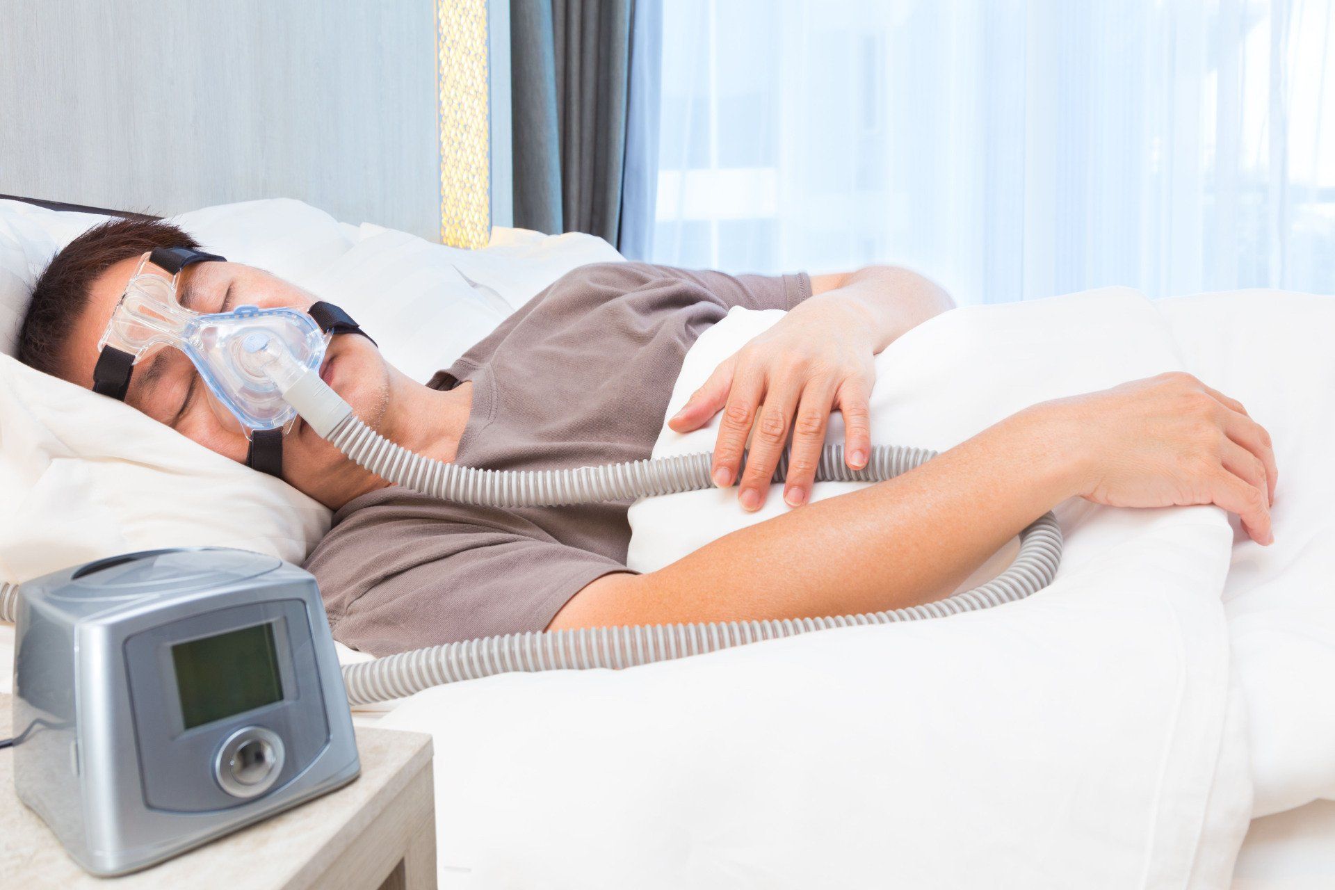 A man is sleeping in a bed with an oxygen mask on his face.