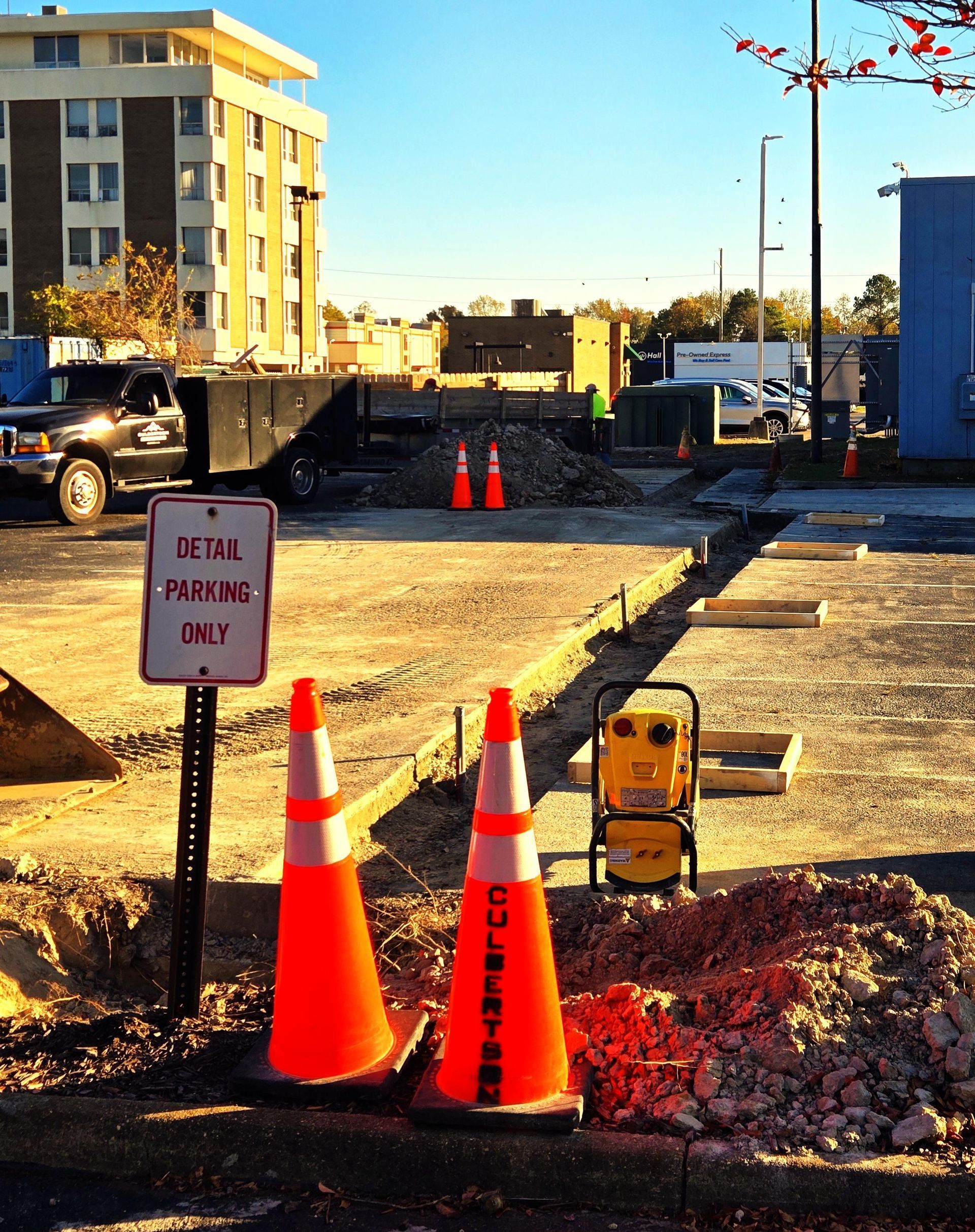 A construction site in a parking lot featuring orange safety cones, a 