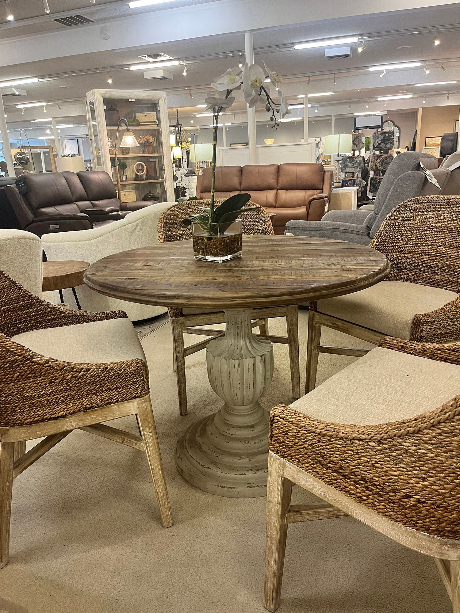 Round wooden table with four woven chairs in furniture store.