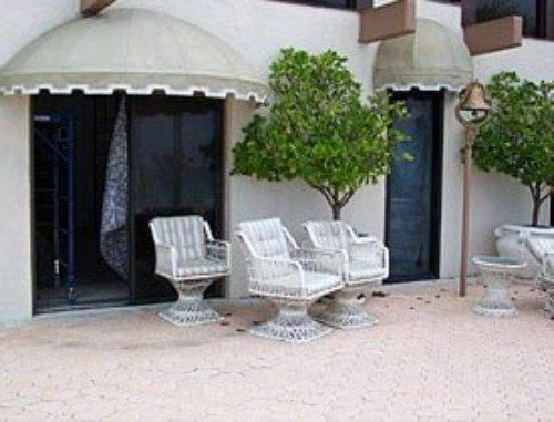 a patio with chairs and trees under an awning