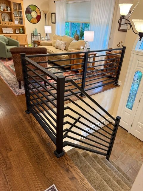 Stairlift chair with black metal frame on a wooden staircase in a living room.
