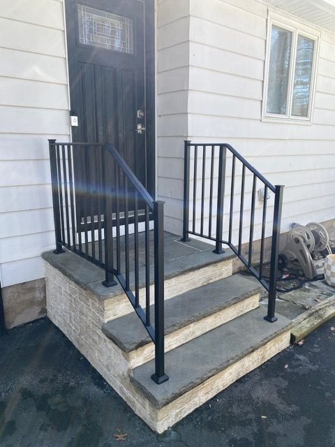 Front steps with black railings leading to a white house entry door
