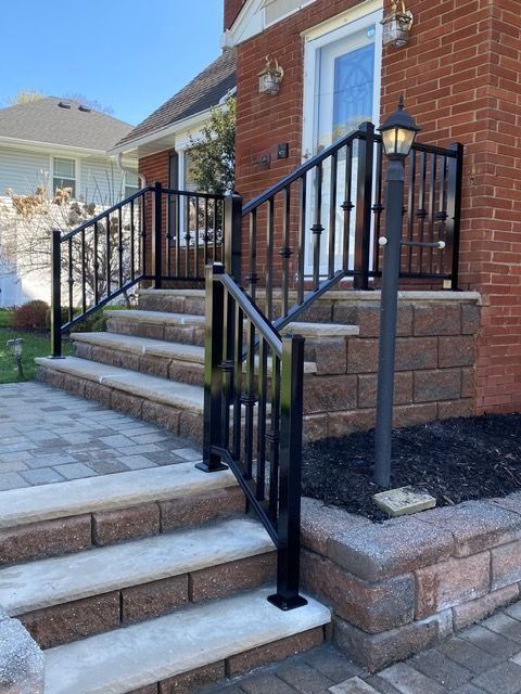 Front steps with black iron railings leading to a brick house entry.