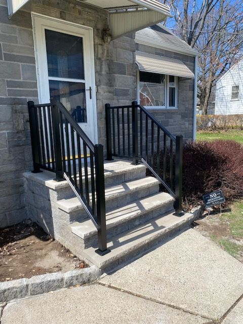 Front entry steps with black railings leading to a house doorway