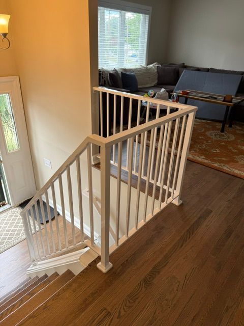 Stair landing with white railing, hardwood floor, and a living room visible in the background.