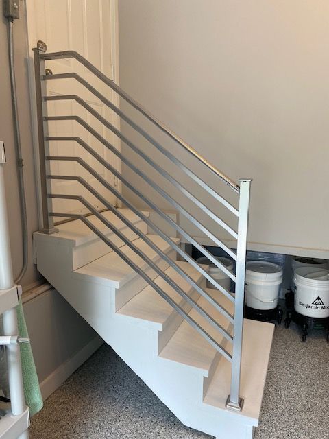Metal staircase with silver railings in a carpeted indoor room
