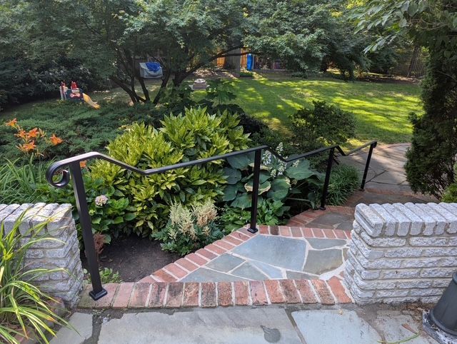 Stone steps with brick borders lead down to a garden with handrails.