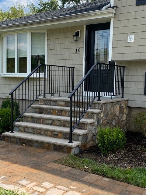 Stone steps lead to a house entrance with black railings.