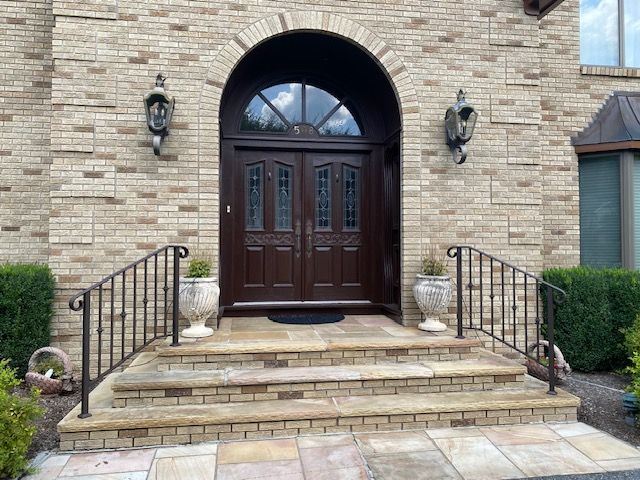 A large brick building with a wooden door and steps leading to it.