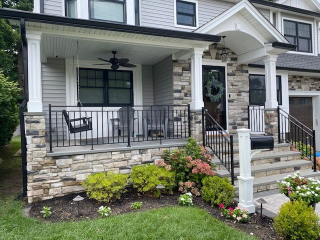 A house with a porch , stairs and a ceiling fan.