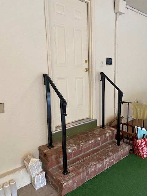 A set of stairs leading up to a door with a black railing.