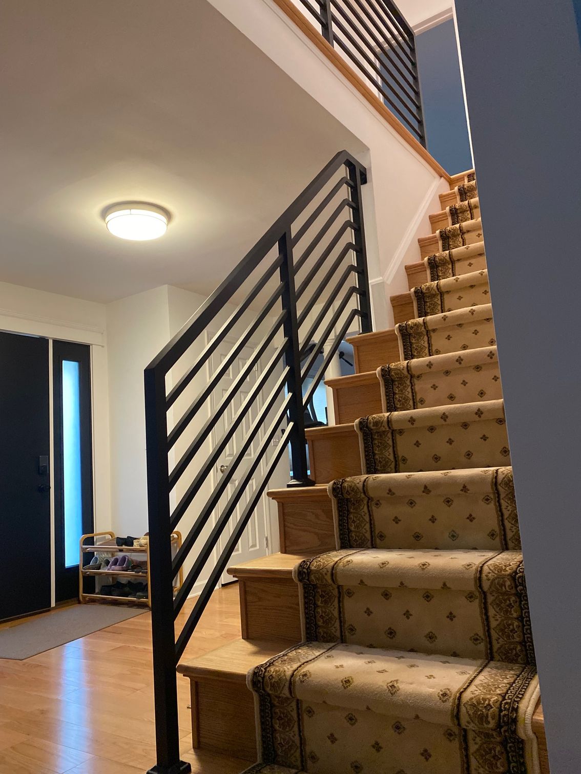 A staircase with a black railing and a carpet on the steps