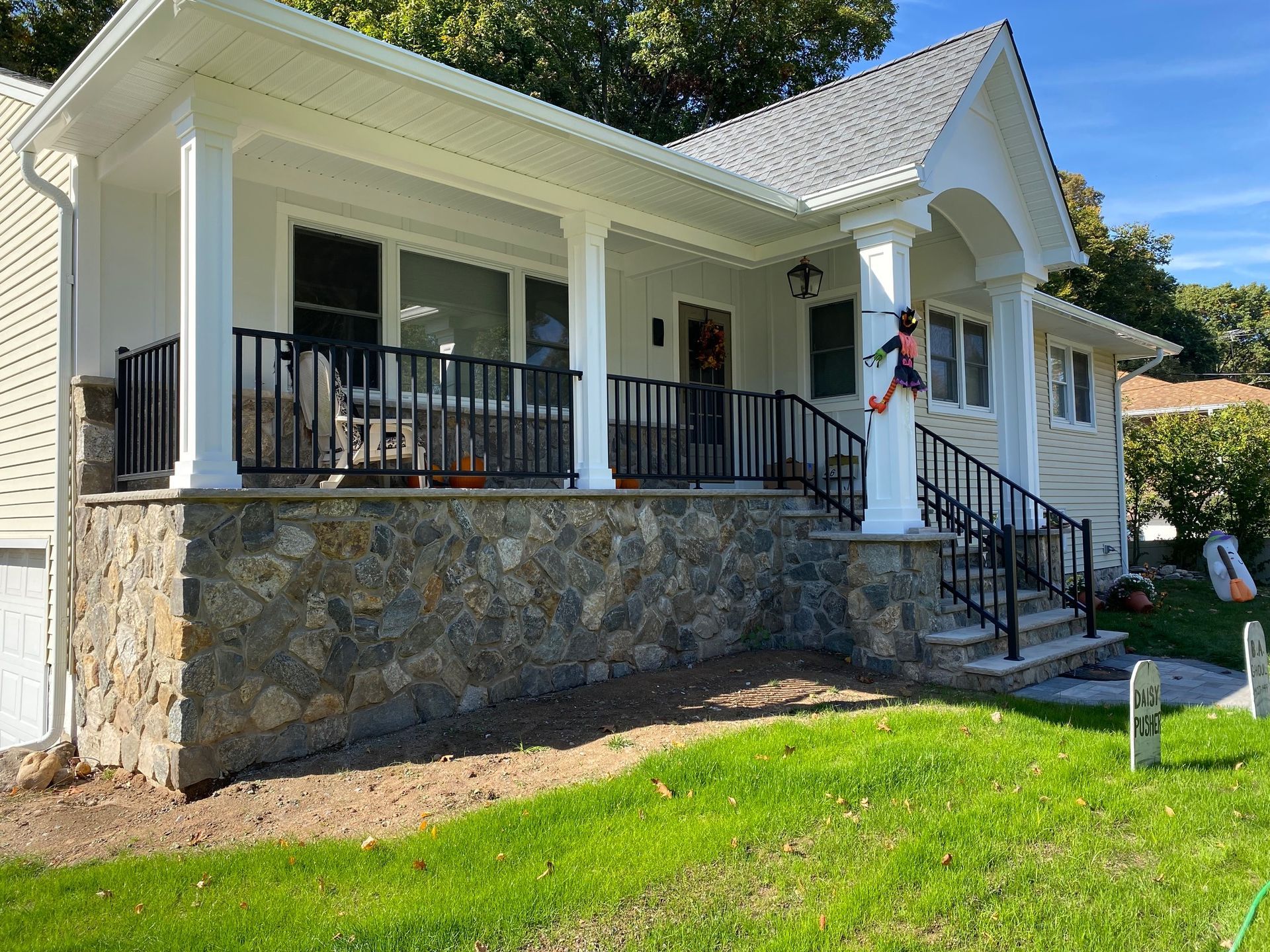A white house with a large porch and stairs.