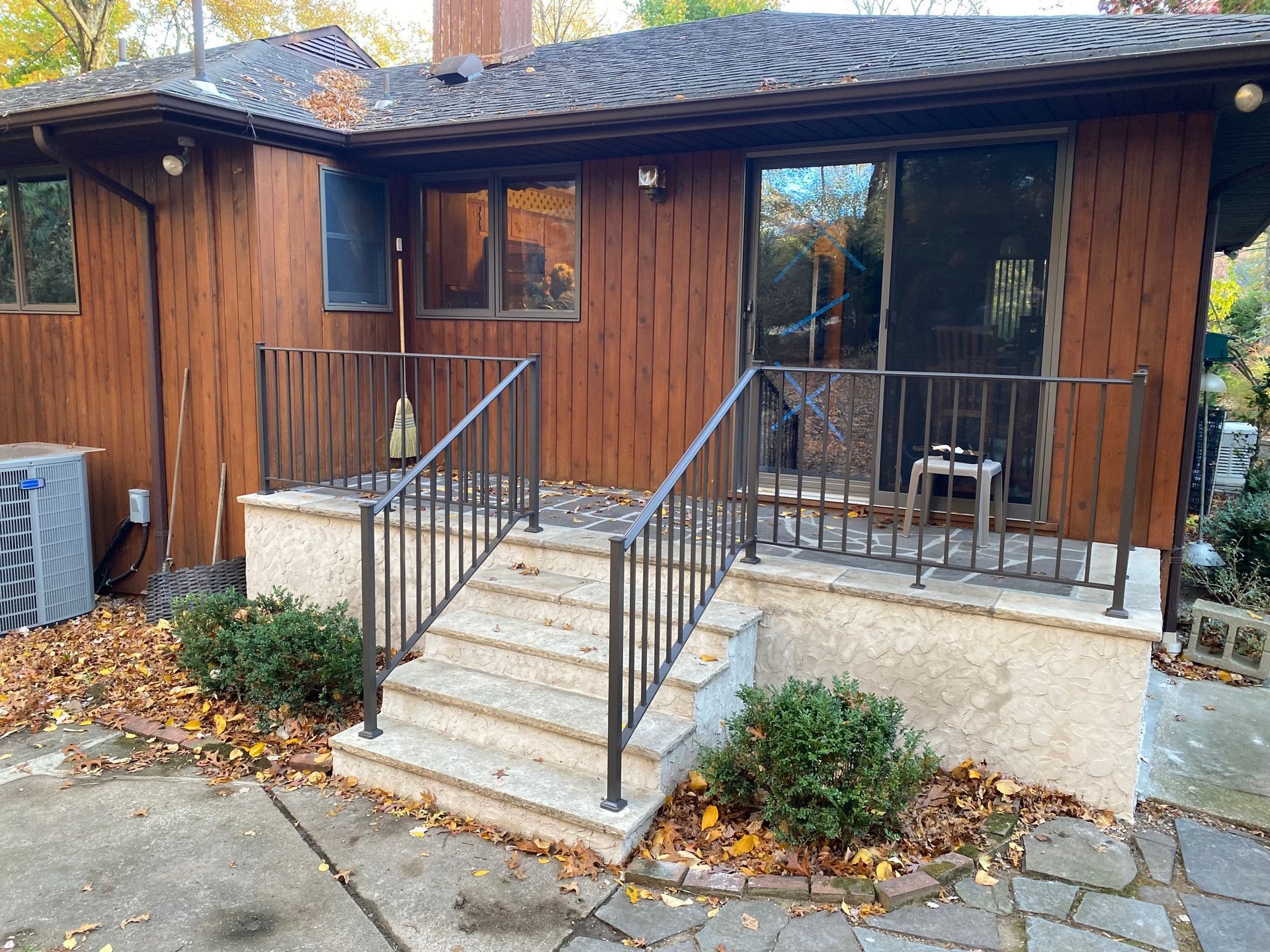 A wooden house with a metal railing and stairs leading to it.