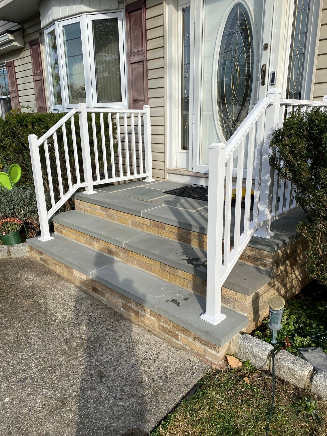 There is a white railing on the front porch of a house.