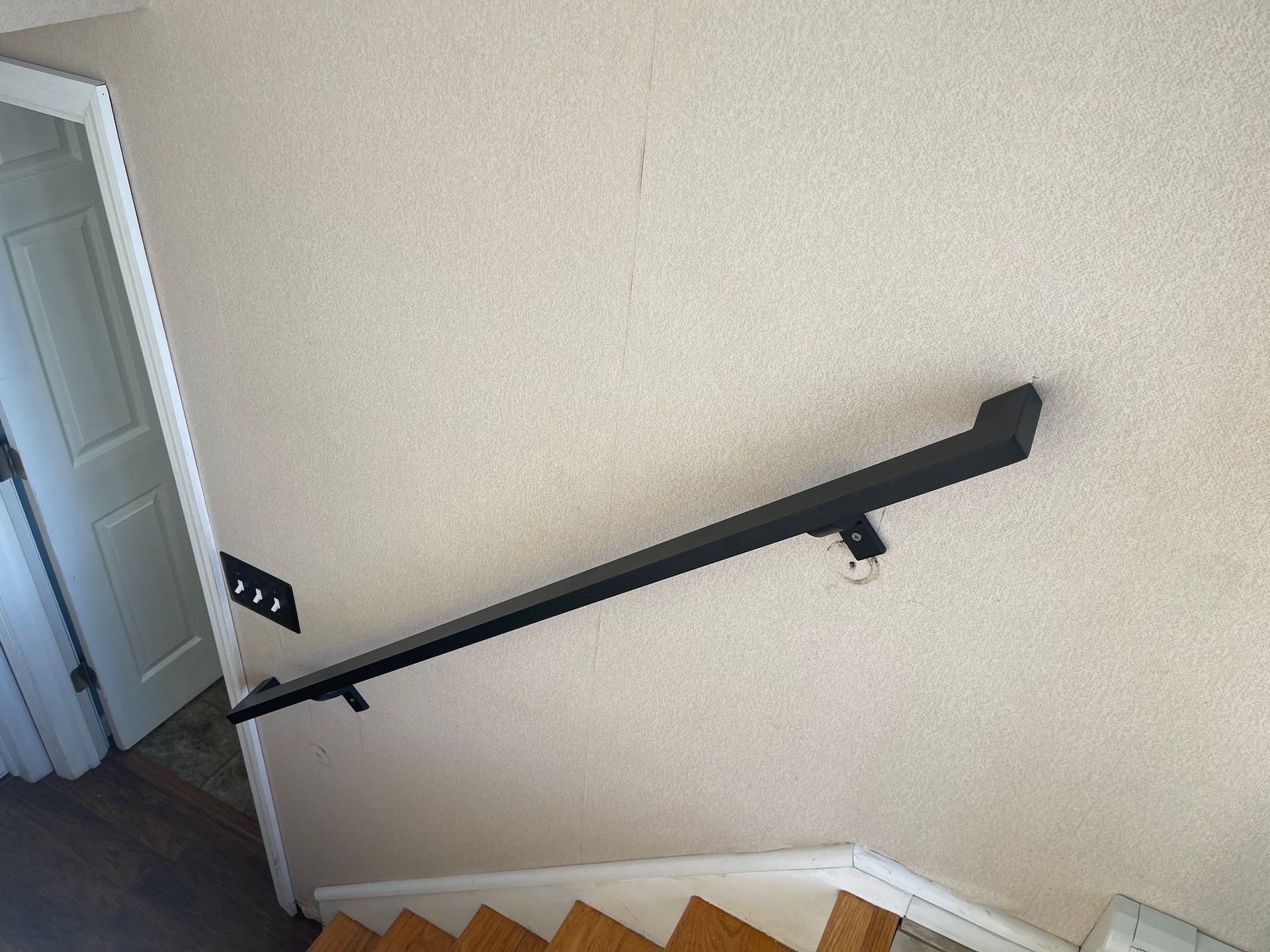 A picture of a staircase with a handrail on the wall.