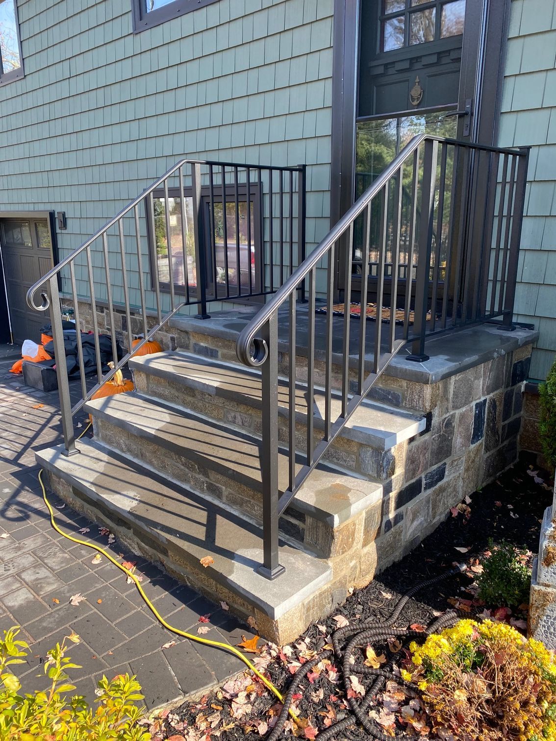 A set of stairs leading up to a house with a wrought iron railing.
