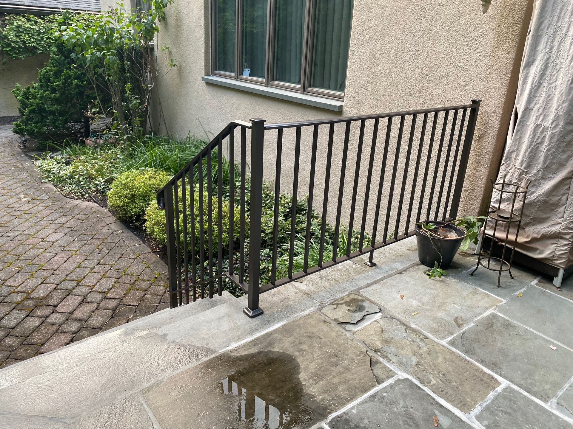 A metal railing is sitting on a patio next to a window.