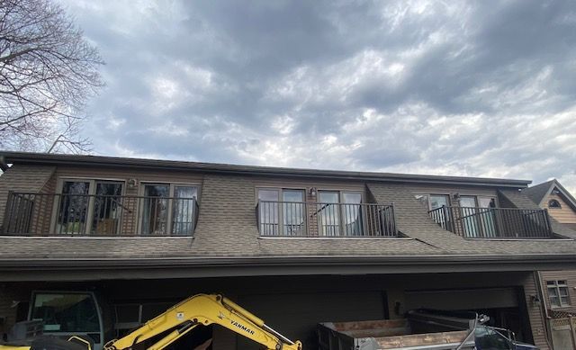 A yellow excavator is parked in front of a house.