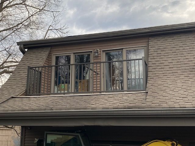 A house with a balcony and a car parked in front of it.