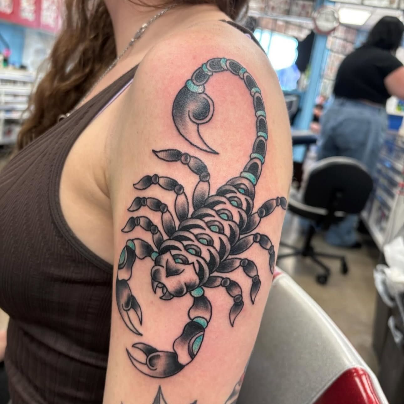 Tattoo of a detailed black scorpion on a person's arm