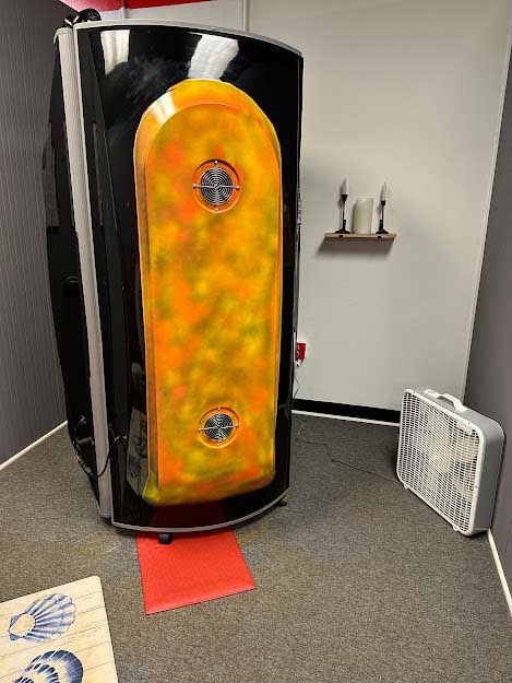 A tanning booth in a small room with a fan.