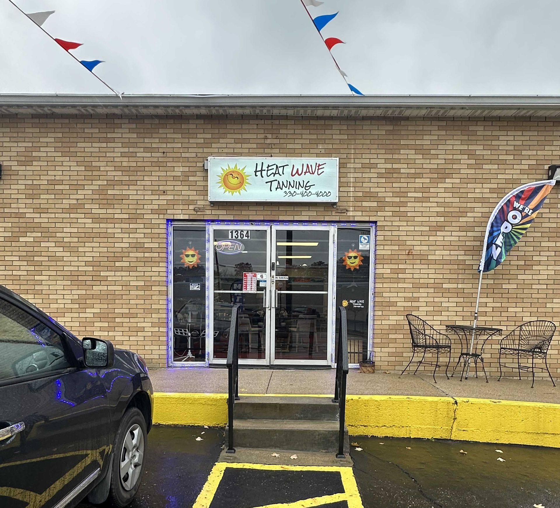 Heat Wave Tanning salon with glass doors, brick facade, and small outdoor seating area.