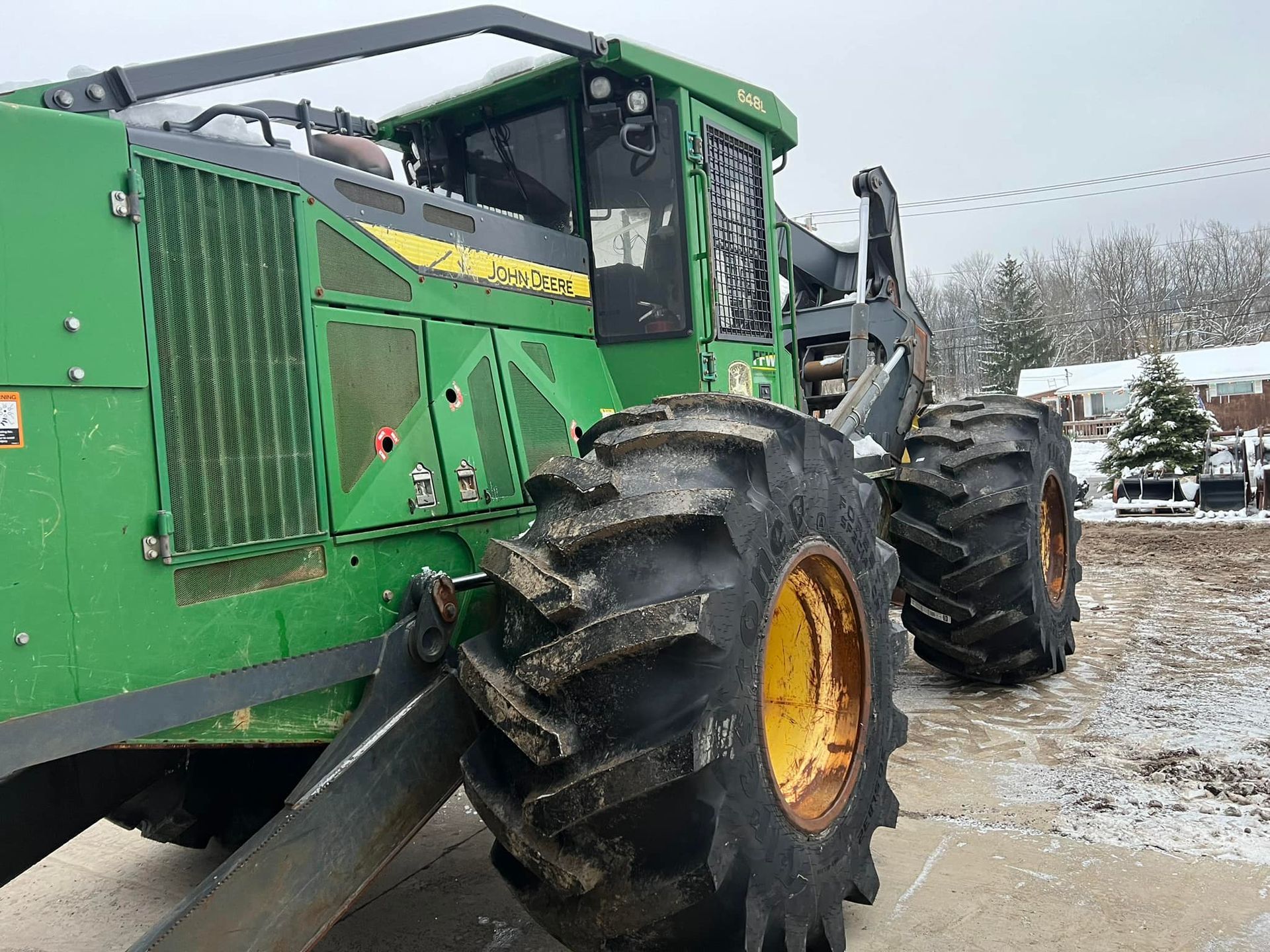 Green John Deere forestry machine with large tires; parked outdoors.