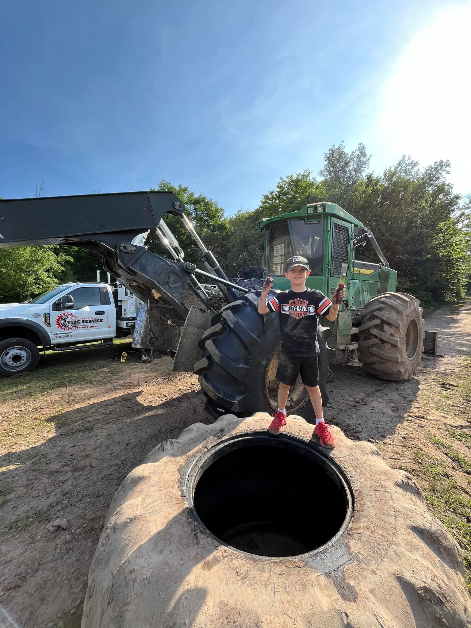 Boy standing near industrial machinery on a sunny day.
