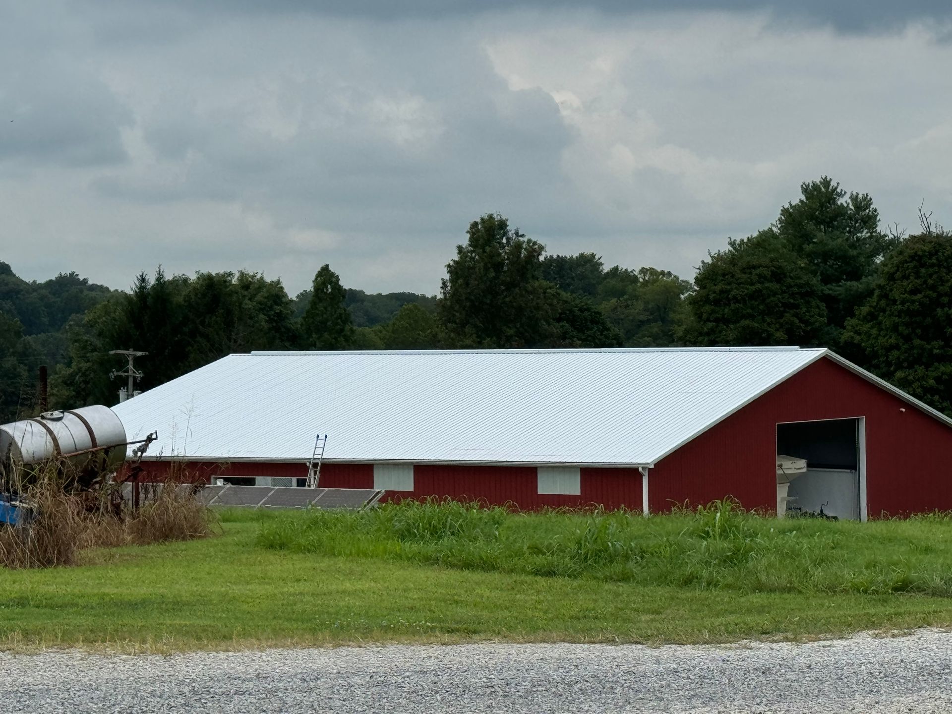 Red barn with white roof in a grassy field under cloudy sky