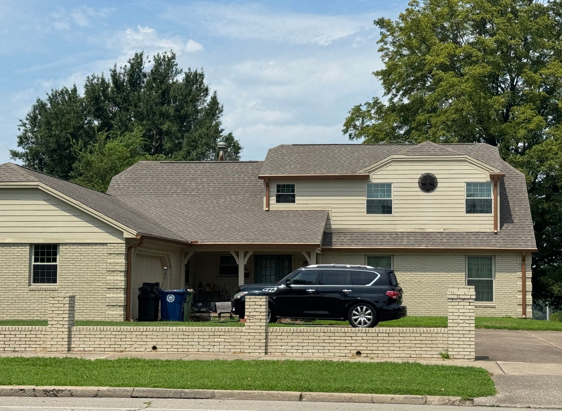 Suburban house with a black SUV parked in the driveway and a green lawn in front