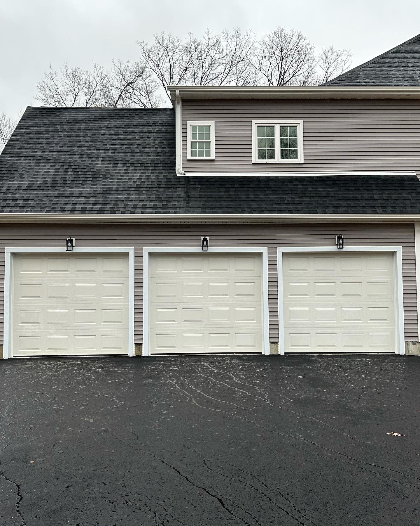 A house with three garage doors and a black roof