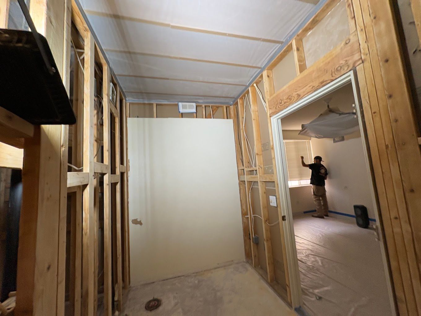 Partially framed interior room under construction with unfinished walls and a person in the next room