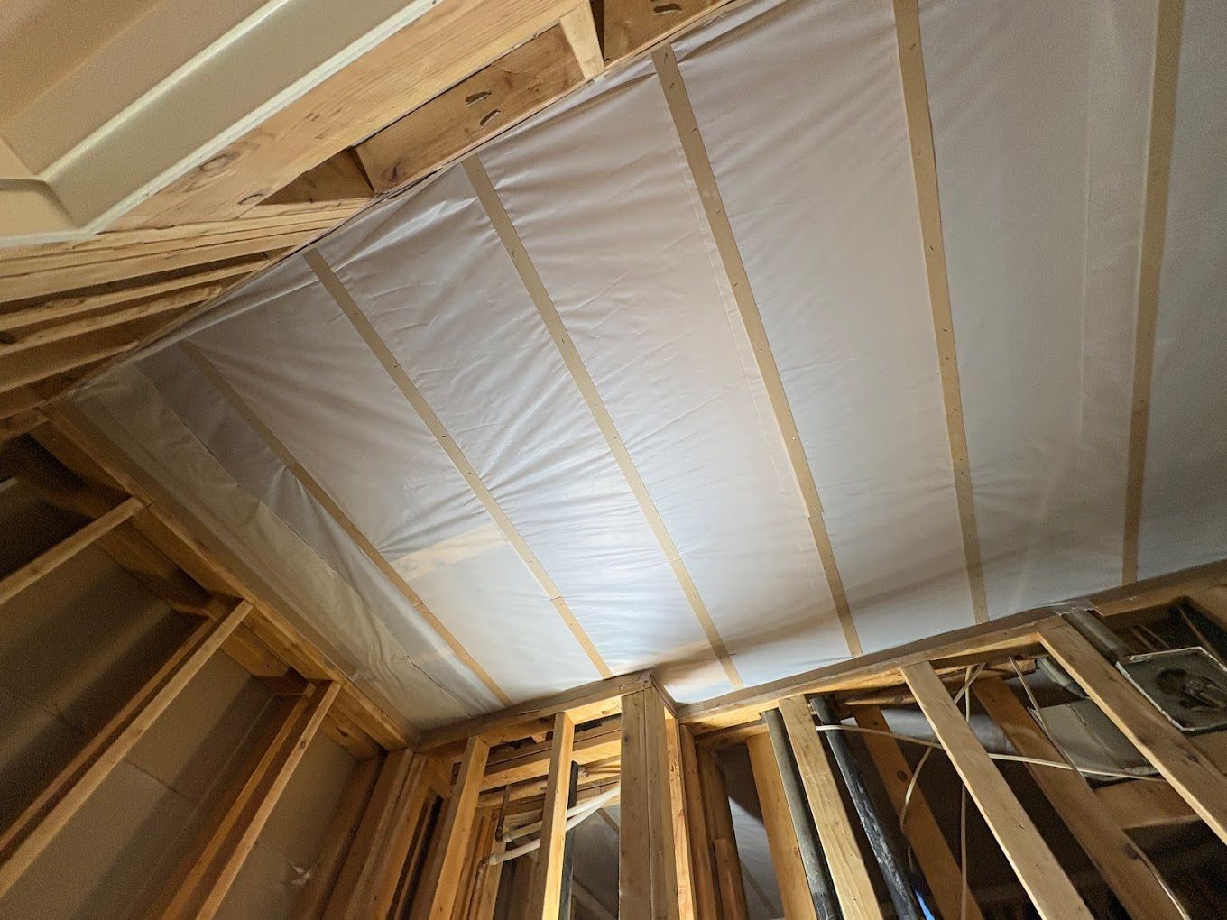Interior of a framed attic with exposed wood rafters and white insulation panels on the ceiling