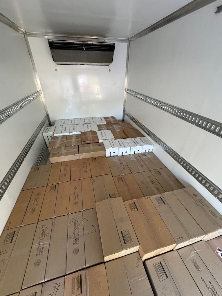 Inside an empty box truck, cardboard panels line the floor with white pallets near the front.