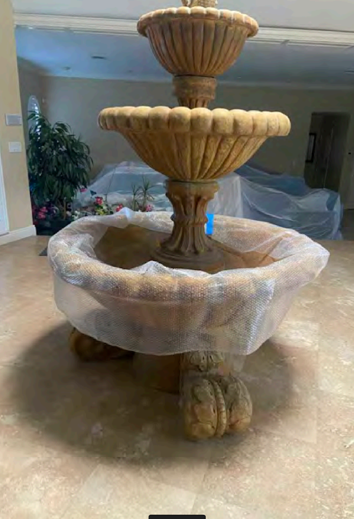Three-tier fountain wrapped in plastic in a room with beige tile floor