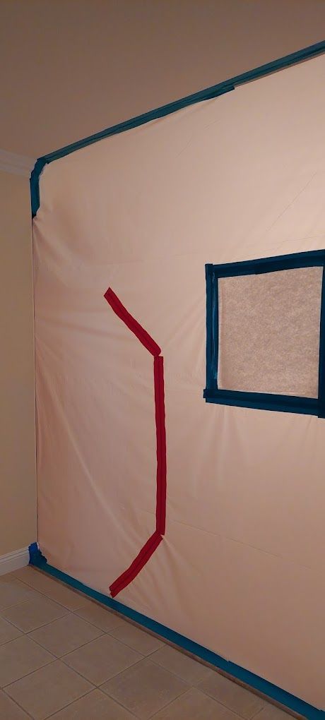 Corner of a room with blue tape outlines and a red curved line on a white wall