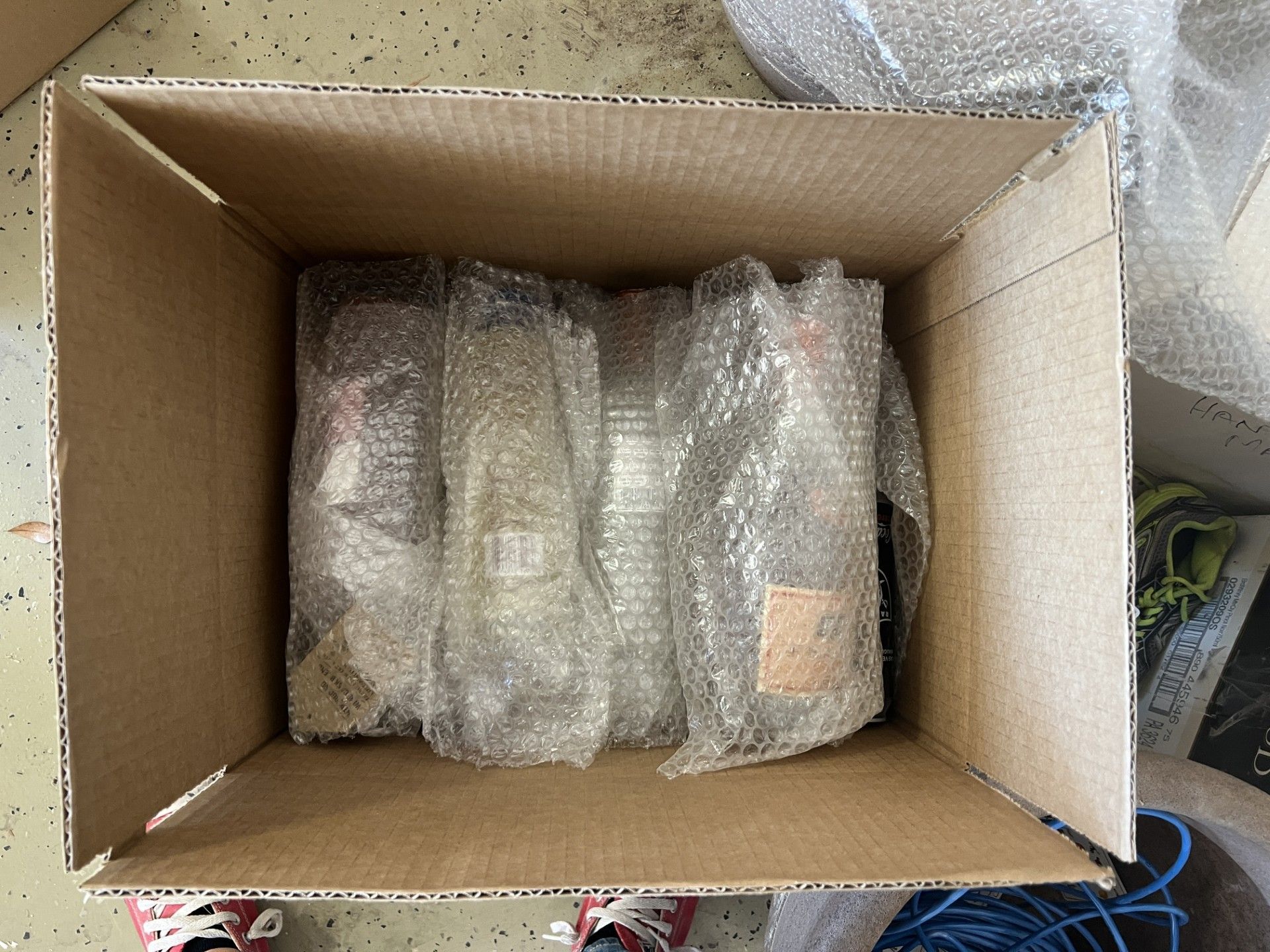 Open cardboard box with bubble-wrapped items inside on a carpeted floor