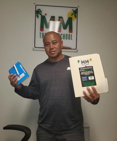 Man holding a blue box and a file folder in an office with a